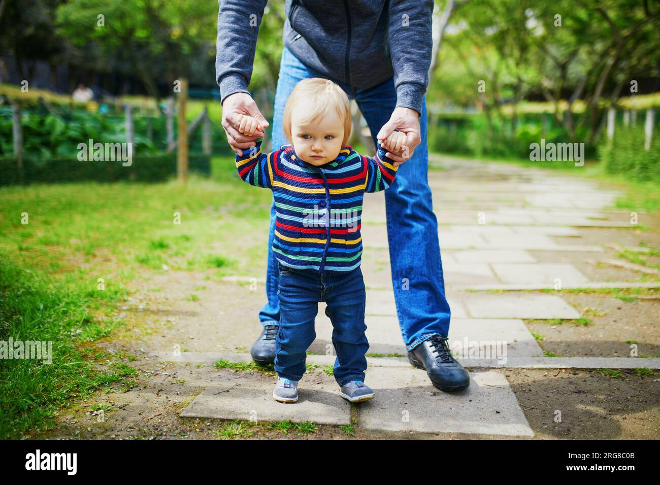 Man with 1 year old baby girl in park. Father helping his daughter make