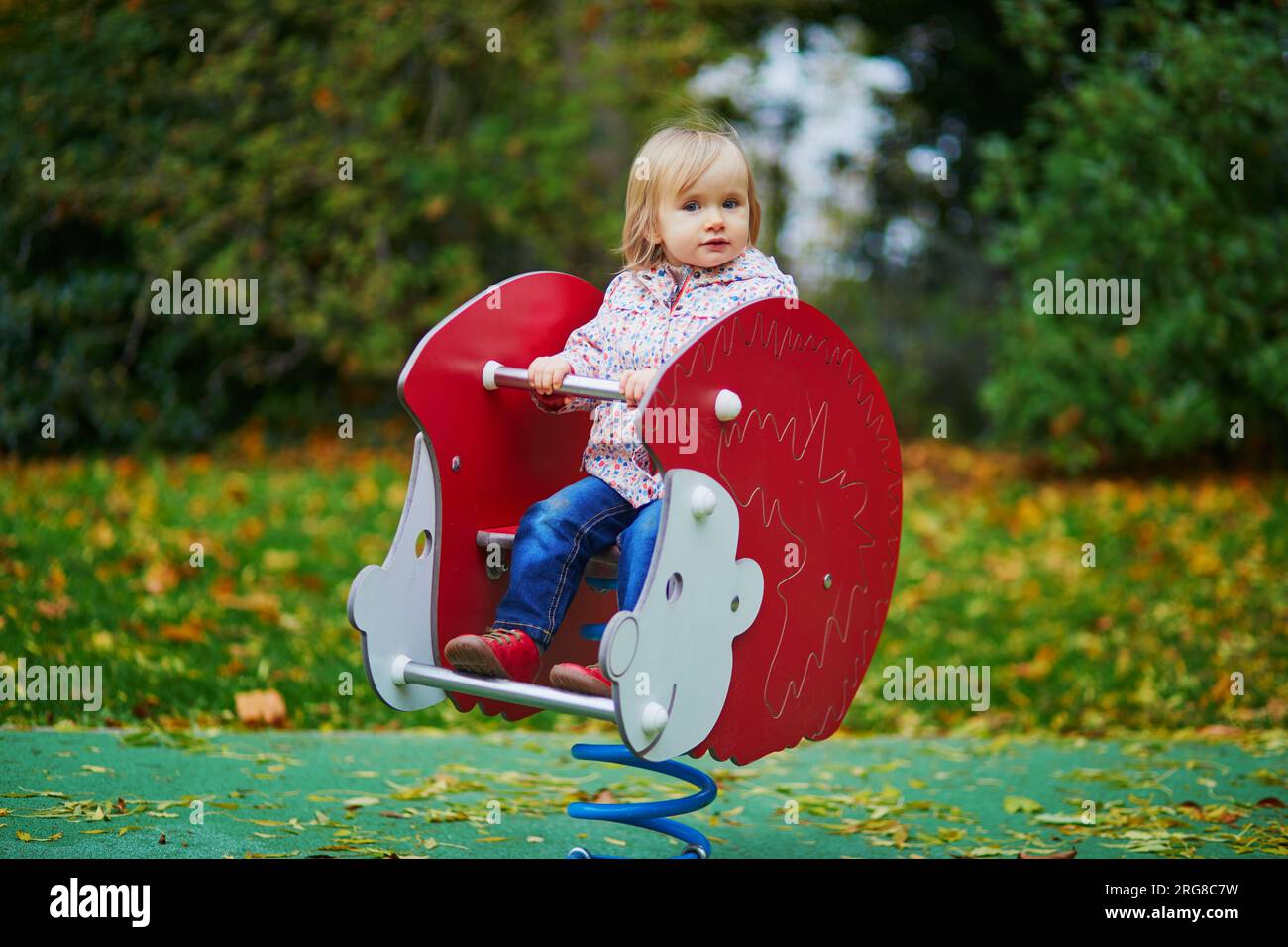 Adorable toddler girl having fun on spring rider on playground on a ...