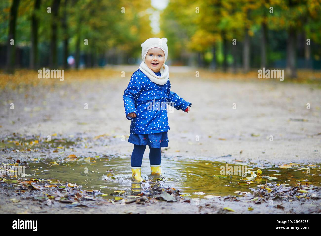 Child wearing yellow rain boots and jumping in puddle on a fall day ...