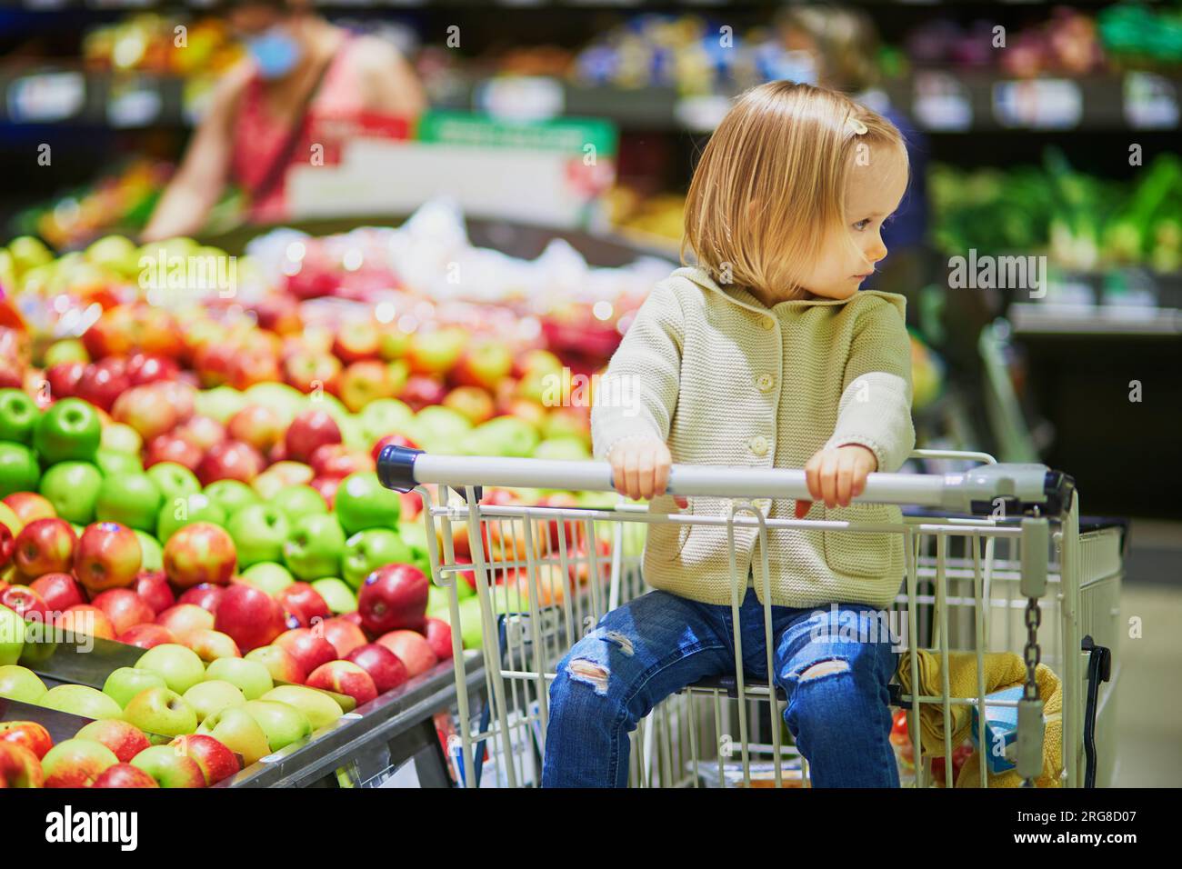 Adorable toddler girl sitting in the shopping cart in a food store or a ...