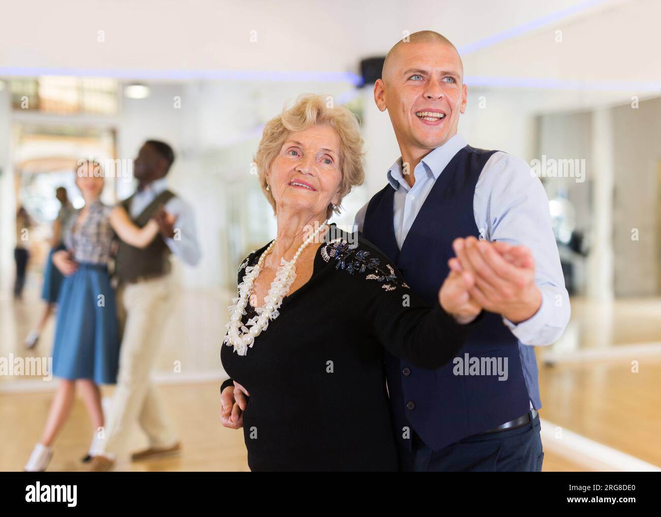 Elderly woman learning ballroom dancing movements in pair Stock Photo ...