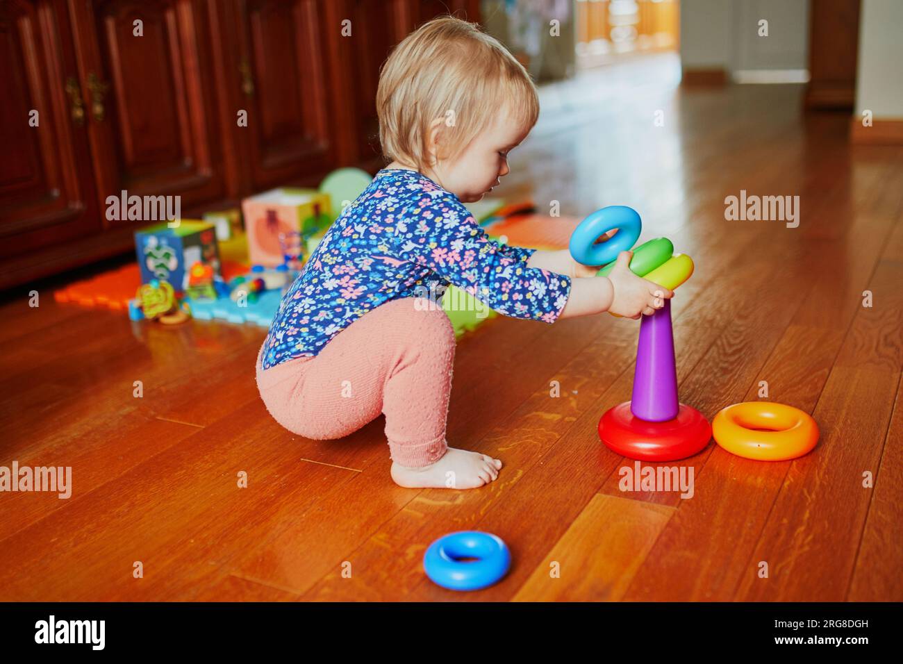 Baby girl playing with toys on the floor. Happy healthy little child at
