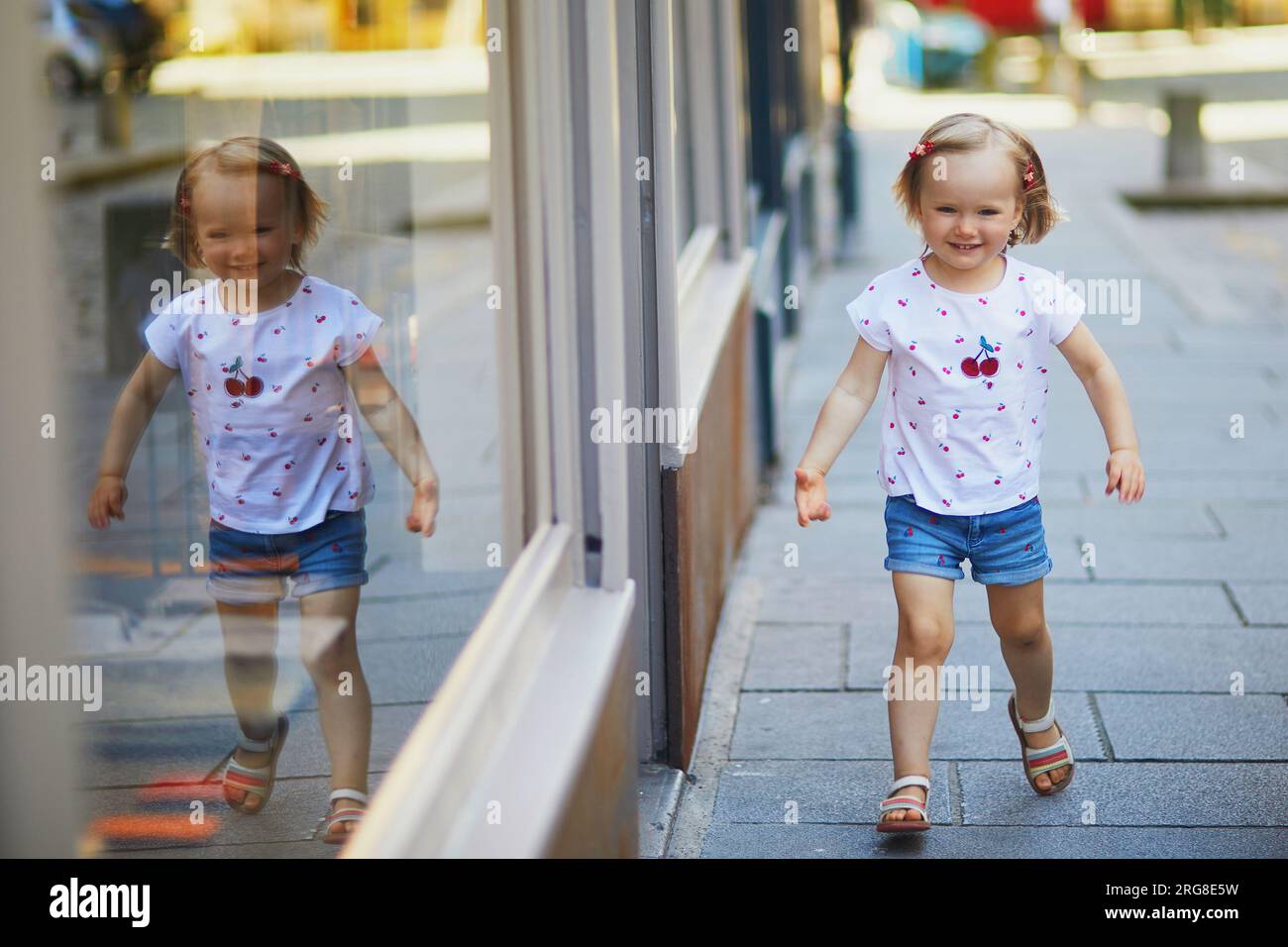Adorable toddler girl having fun outdoors on a sunny summer day. Happy child walking in city. Outdoor activities for kids Stock Photo
