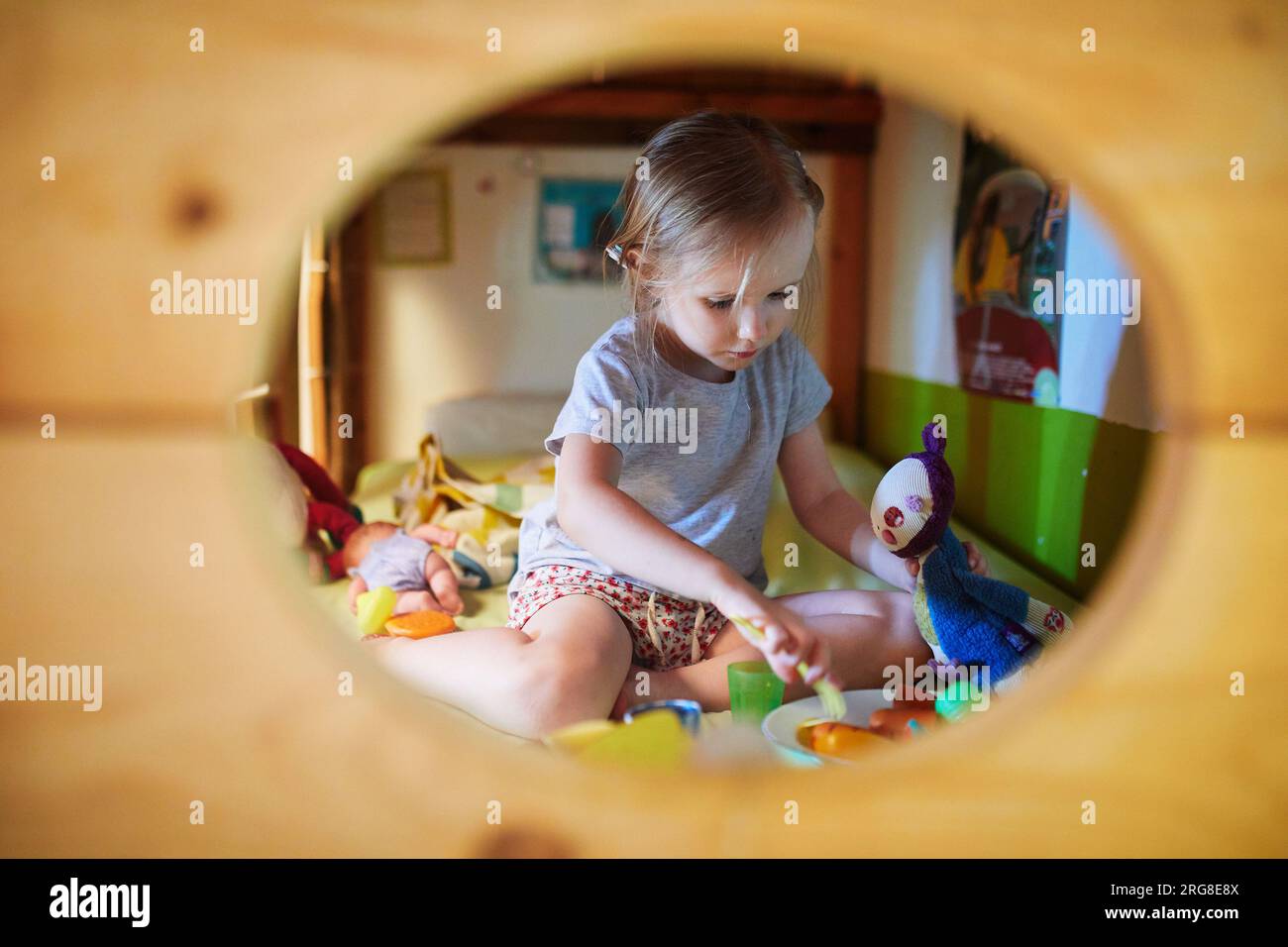 Adorable preschooler girl playing with dolls and toys on bunk bed at home. Indoors activities for kids Stock Photo