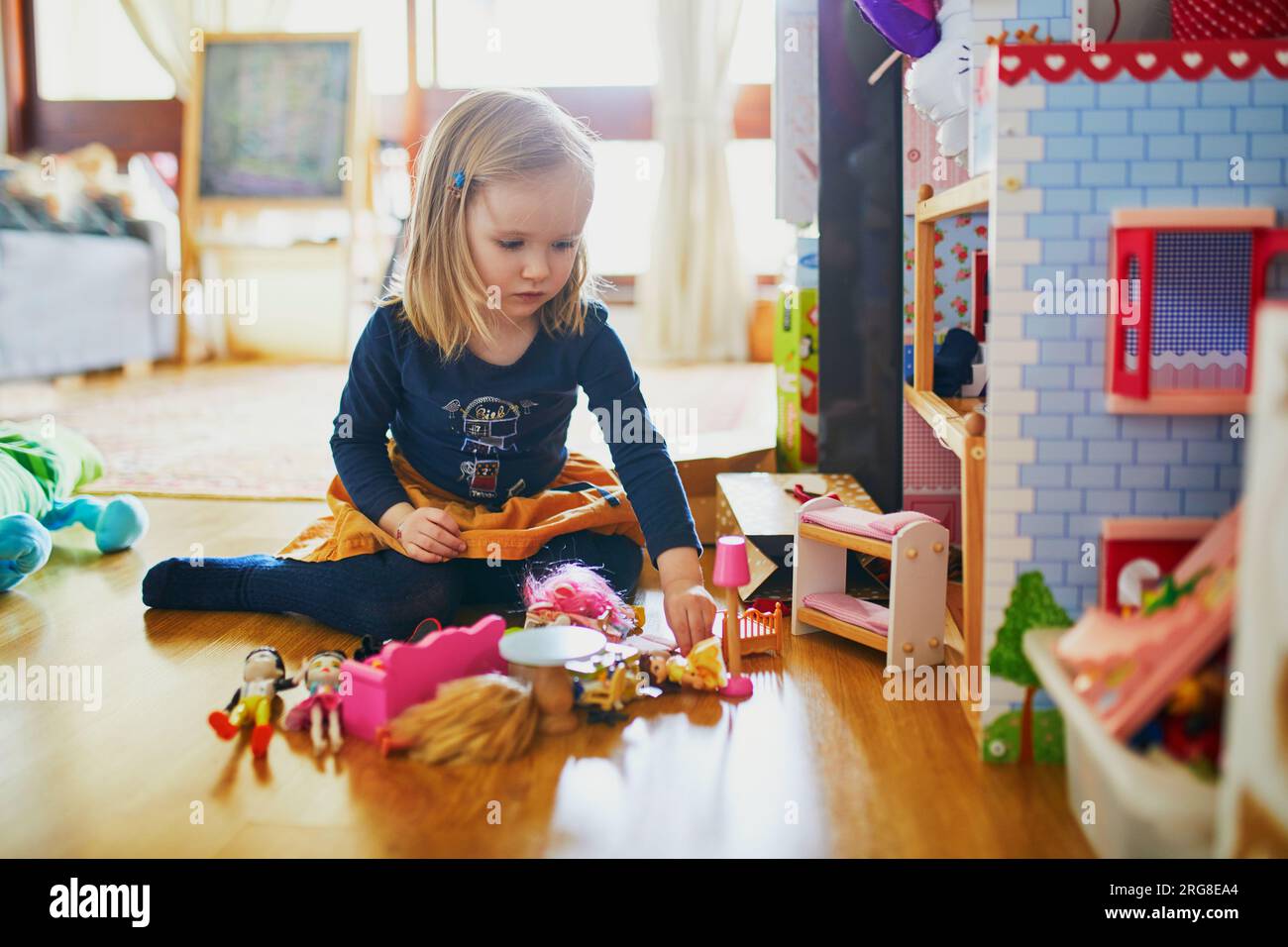 adorable-toddler-girl-having-fun-with-doll-house-in-playroom-at-home