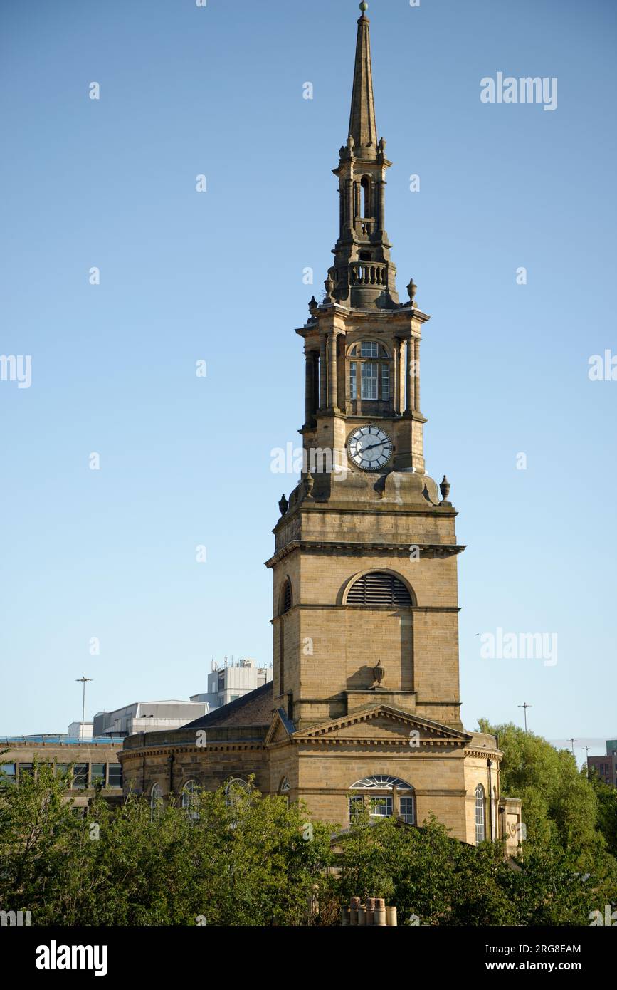 A church building of Newcastle Upon Tyne, England. Honey coloured stone of the North East on a sunny morning. Spire with clock in the tower. Stock Photo