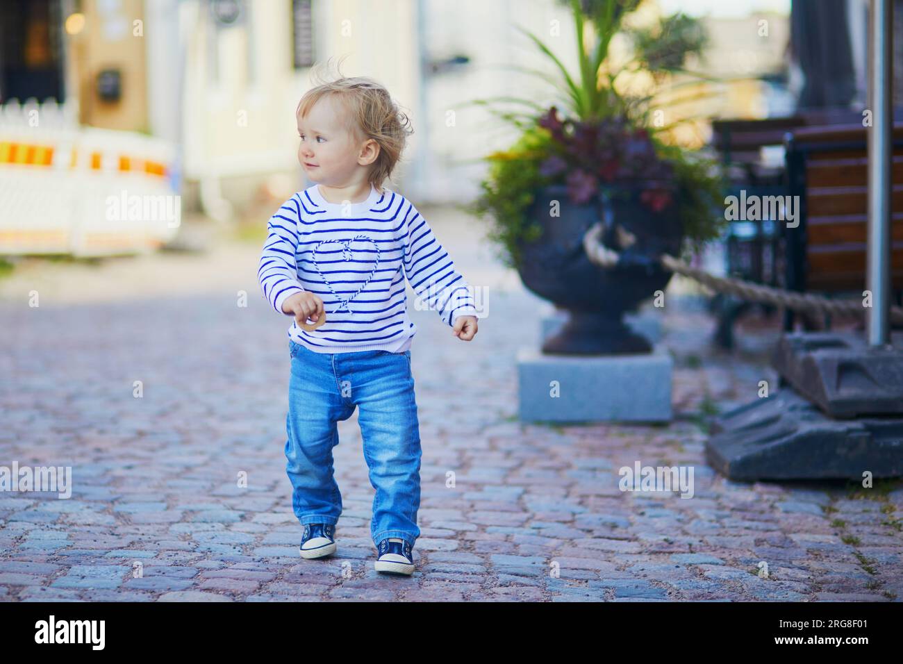 Happy smiling toddler walking in the street of Finnish town Porvoo, Finland Stock Photo