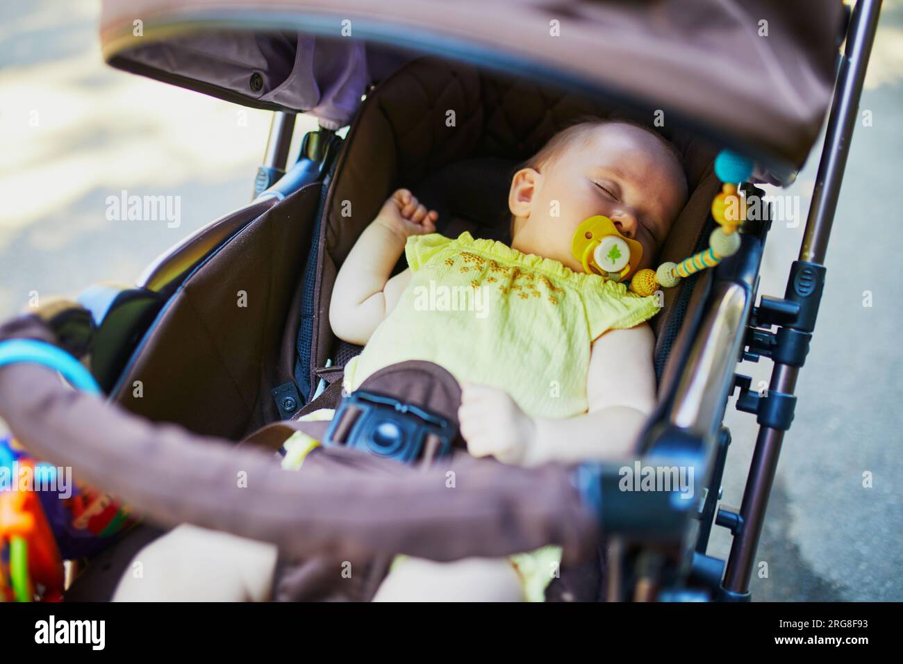 Baby girl sleeping in stroller. Little child in pram. Infant kid outdoors in pushchair Stock Photo