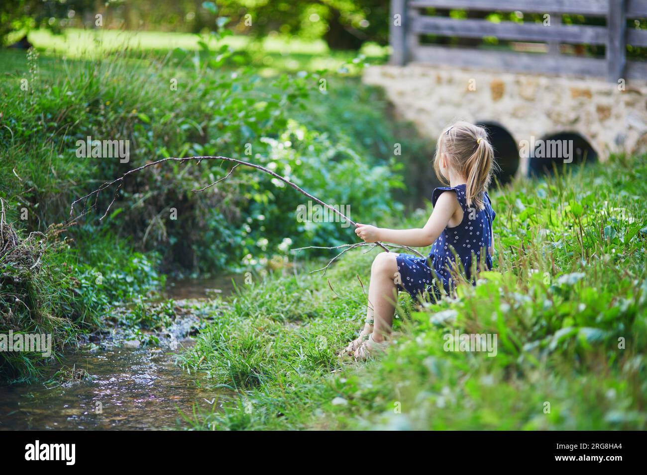 Preschooler girl playing with a twig like with fishing rod. Role games