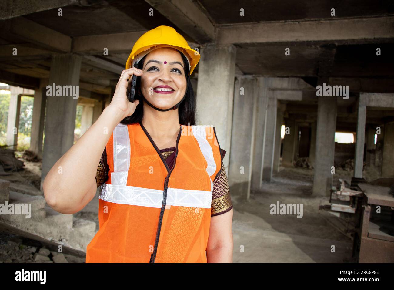 Indian female civil engineer wearing helmet and vest standing at