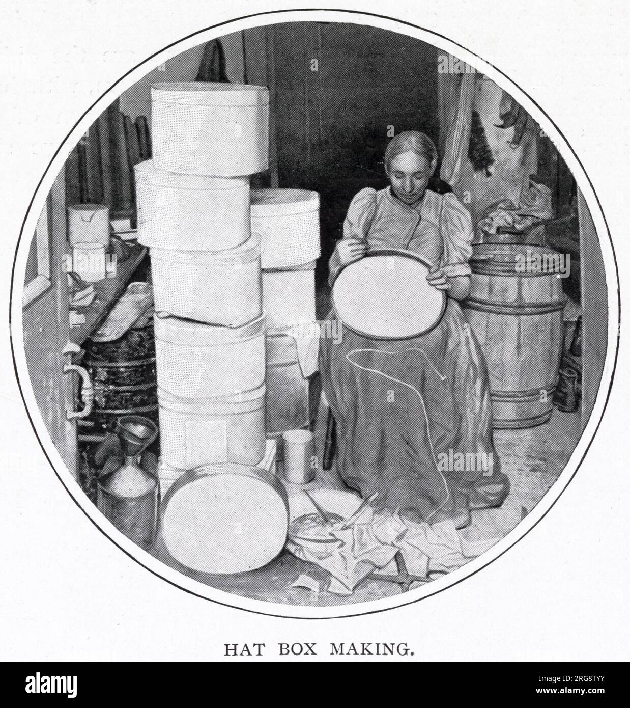 Woman sitting in her own home in South London, making the hat boxes for a supplier that makes silk hats for the richer society. The hat boxes are covered with glazed paper which is stuck together with paste and the bottom of the box are sewn together with thread. When she completes a gross (144), she will receive half-a-crown. Stock Photo