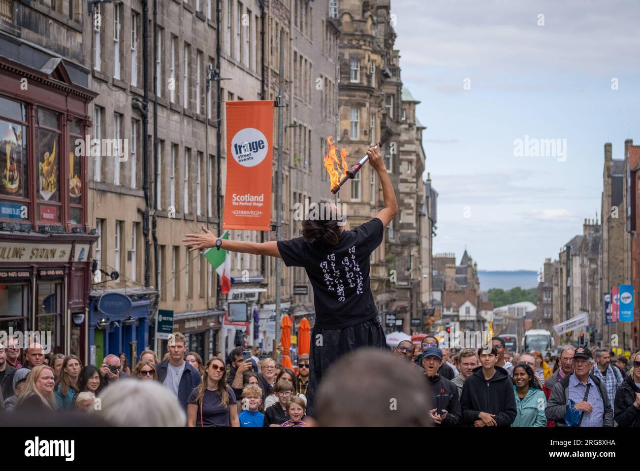 A fire eating street performer surrounded by crowds performs on the Royal Mile in Edinburgh during the Fringe festival, August 2023. Scotland, UK. Stock Photo
