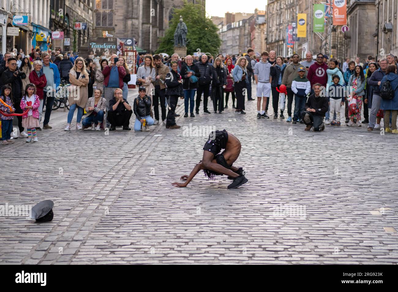 A member of Guinea act 'Afrique En Cirque' performs a contortion act on the Royal Mile in Edinburgh during the Fringe Festival, August 2023. Scotland. Stock Photo