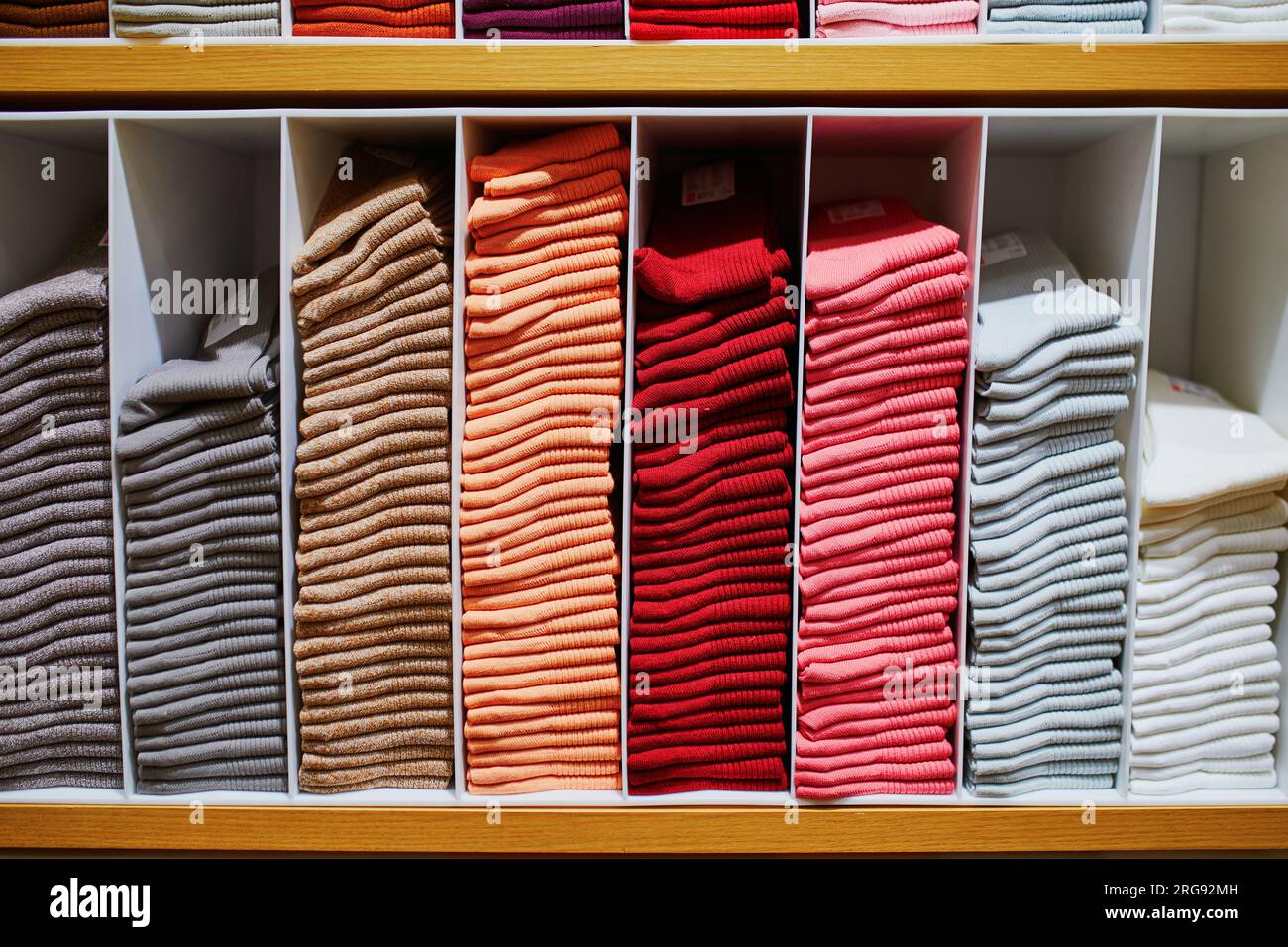 Cotton socks folded neatly in the clothing showroom. Multi-colored socks folded in brightly colored wardrobes. Shelves and colorful clothes in large s Stock Photo