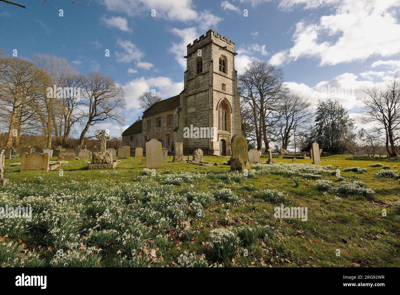 A view of Baddesley Clinton parish church, near Kenilworth in Warwickshire, with snowdrops in the foreground.  Dedicated to St Michael, building began in the 13th century. Stock Photo