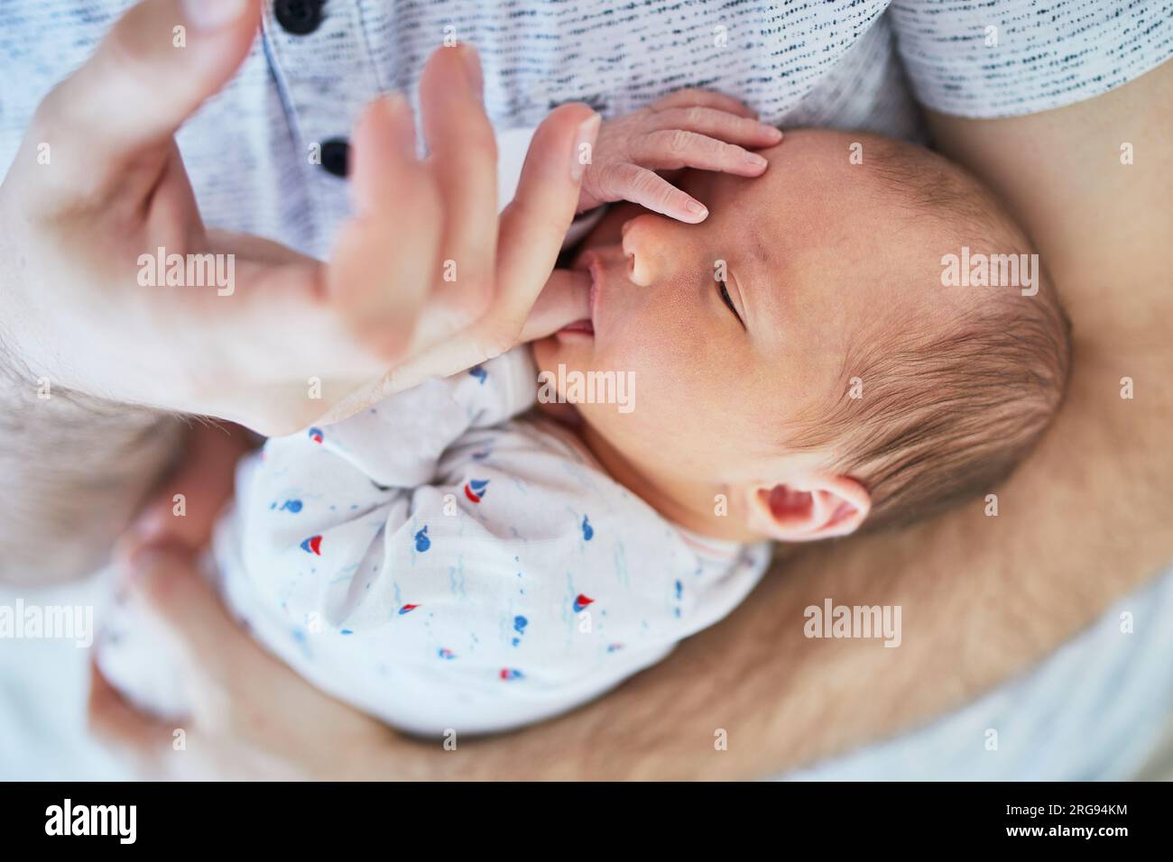 Adorable newborn baby girl sleeping on her father's chest and sucking