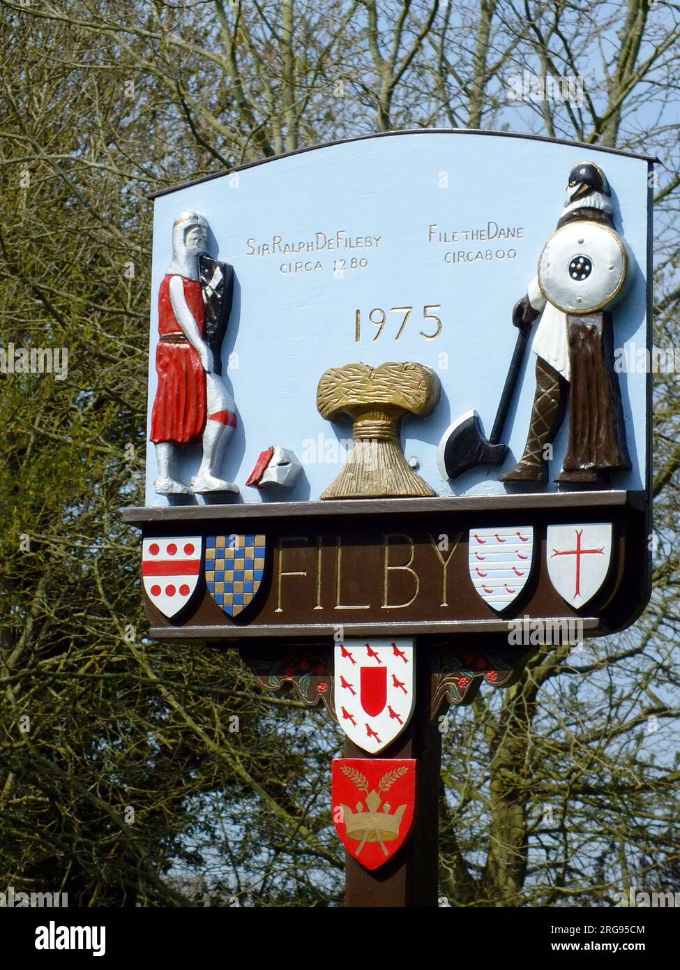 Village sign for Filby, near Great Yarmouth, Norfolk, dated 1975, depicting two historical figures -- File the Dane, who settled in the area around the year 800, and Sir Ralph de Fileby, who lived in the area around 1280. Stock Photo
