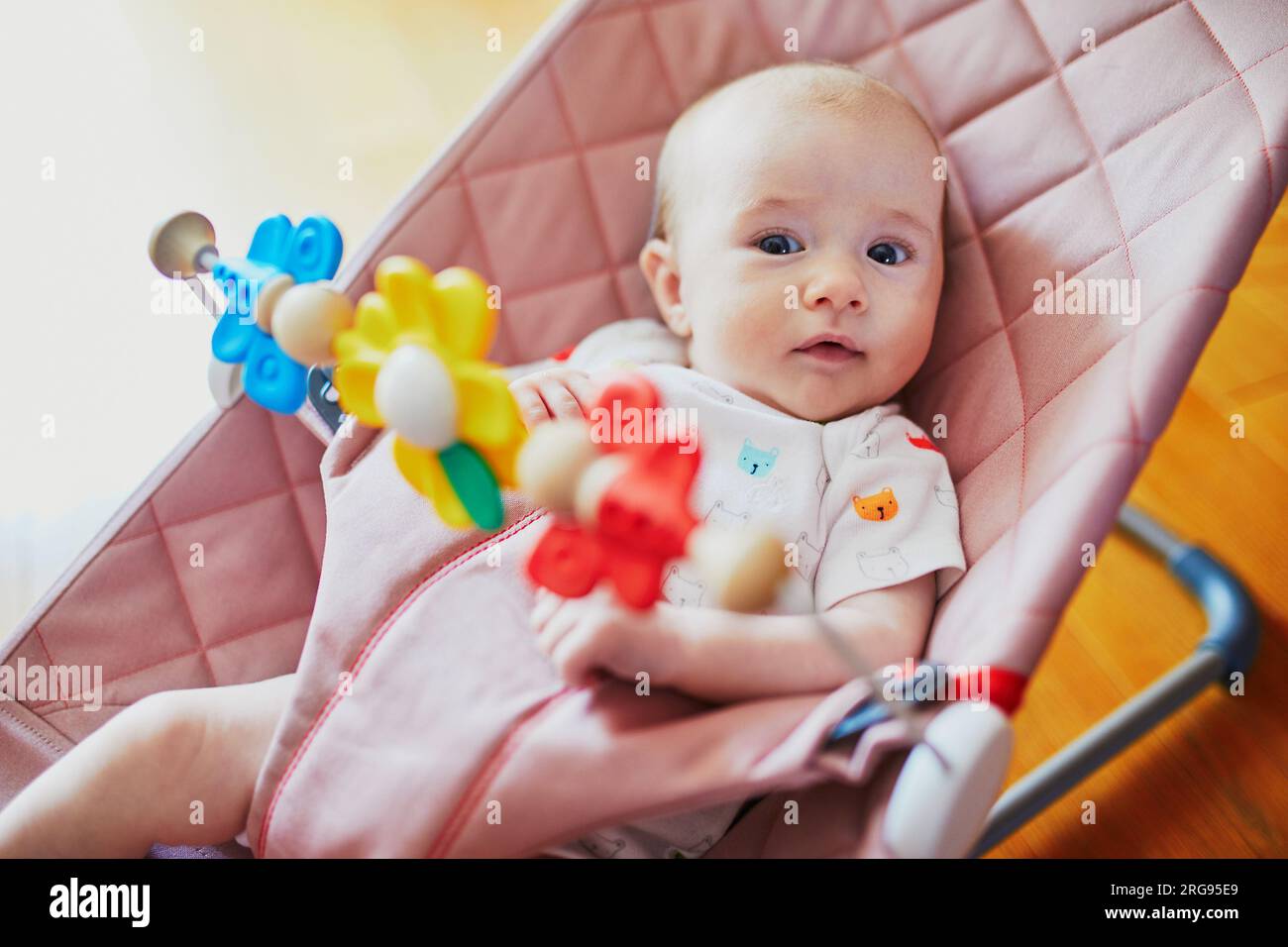 Baby girl playing with toys in bouncer. Little child having fun. Activities for infants Stock Photo