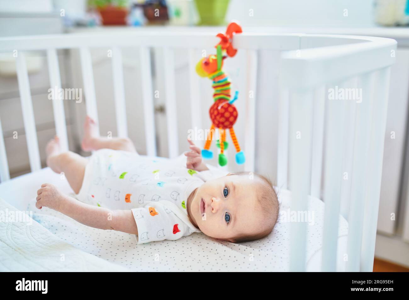 Adorable baby girl lying in the crib. Little child having a day nap in