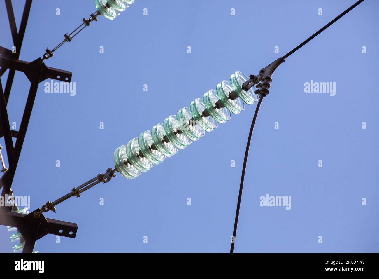 High voltage glass electrical insulator electric line against the blue sky close up Stock Photo