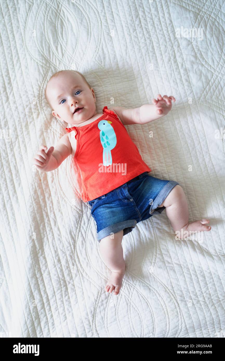 Six months old baby girl lying on her back and laughing. Happy kid
