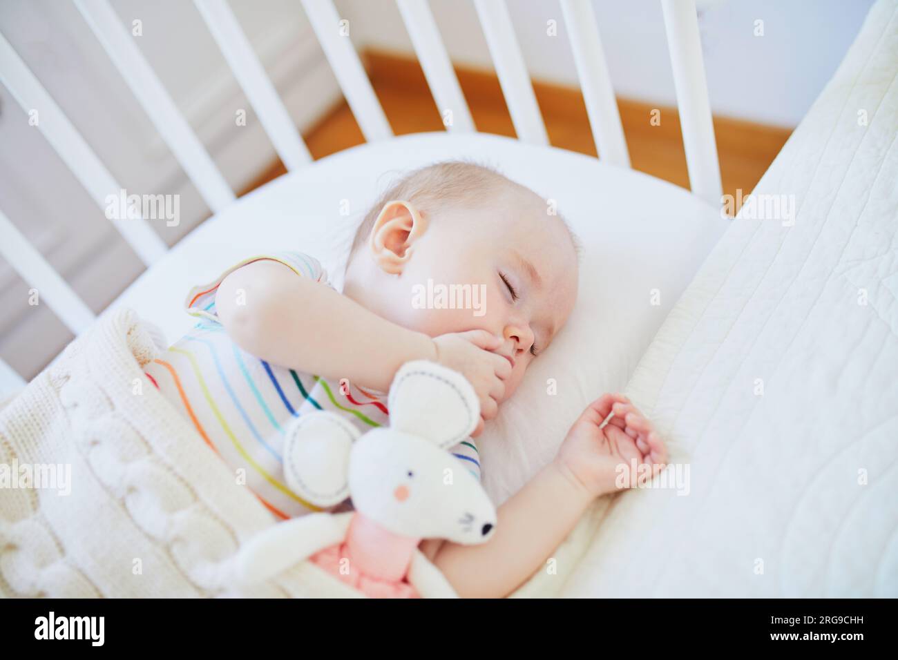 Adorable baby girl sleeping in cosleeper crib attached to parents' bed