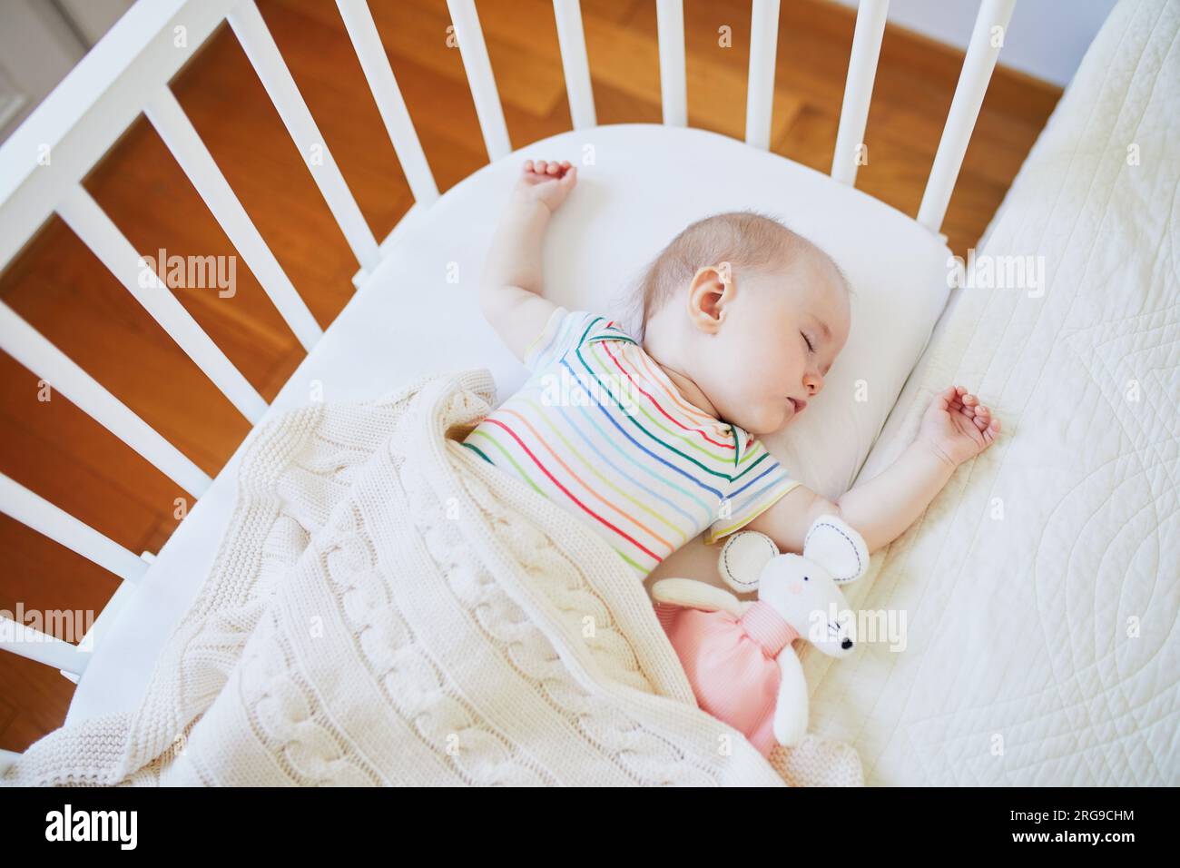 Adorable baby girl sleeping in cosleeper crib attached to parents' bed