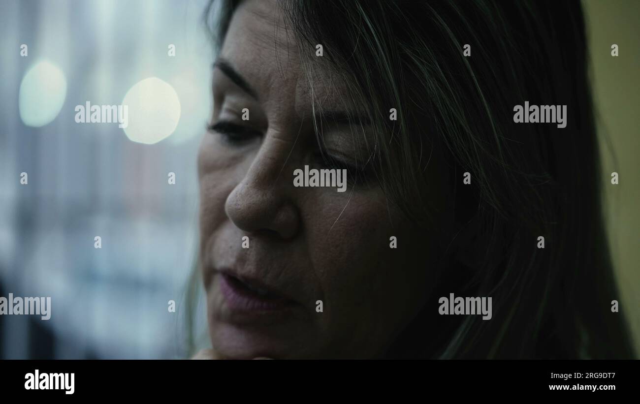 Mature woman with worried emotion, close-up face looking down in sorrow and grief. 50s person in melancholy Stock Photo