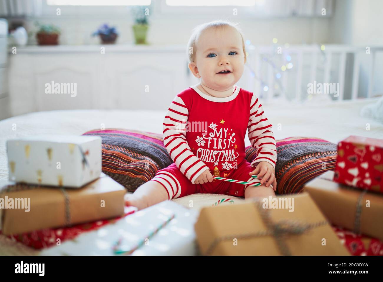 Happy little baby girl wearing pyjamas opening Christmas presents