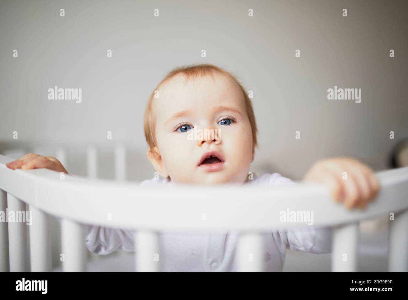 Adorable baby girl in cosleeper crib attached to parents bed. Little