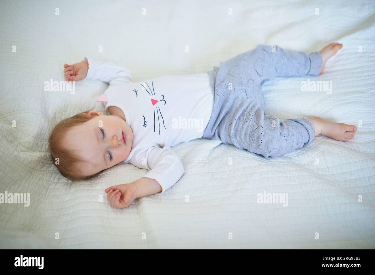 Adorable baby girl sleeping in crib. Small kid having day nap in