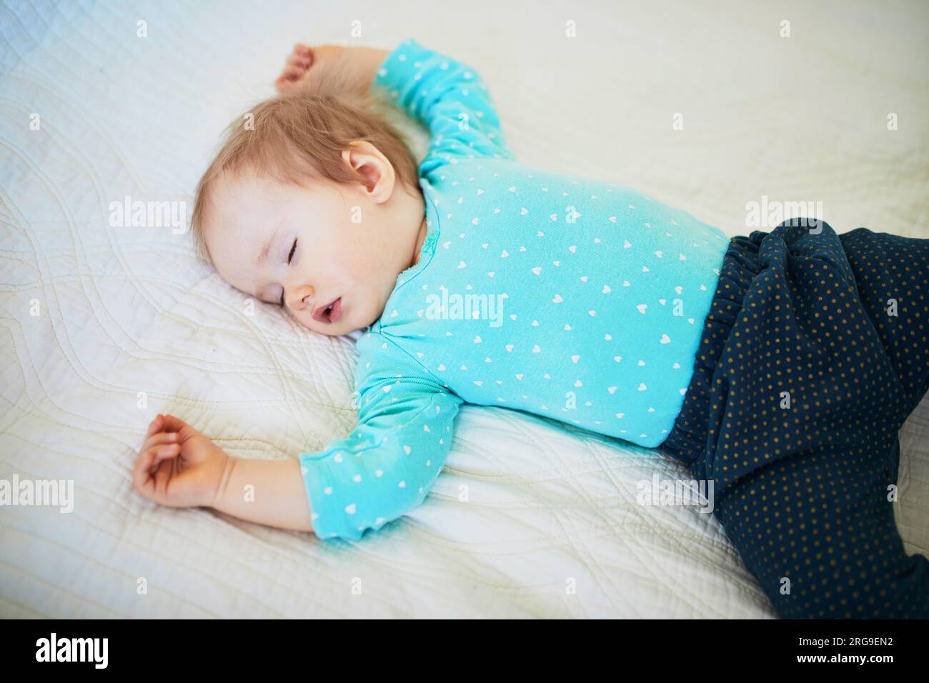 Adorable baby girl sleeping in crib. Small kid having day nap in