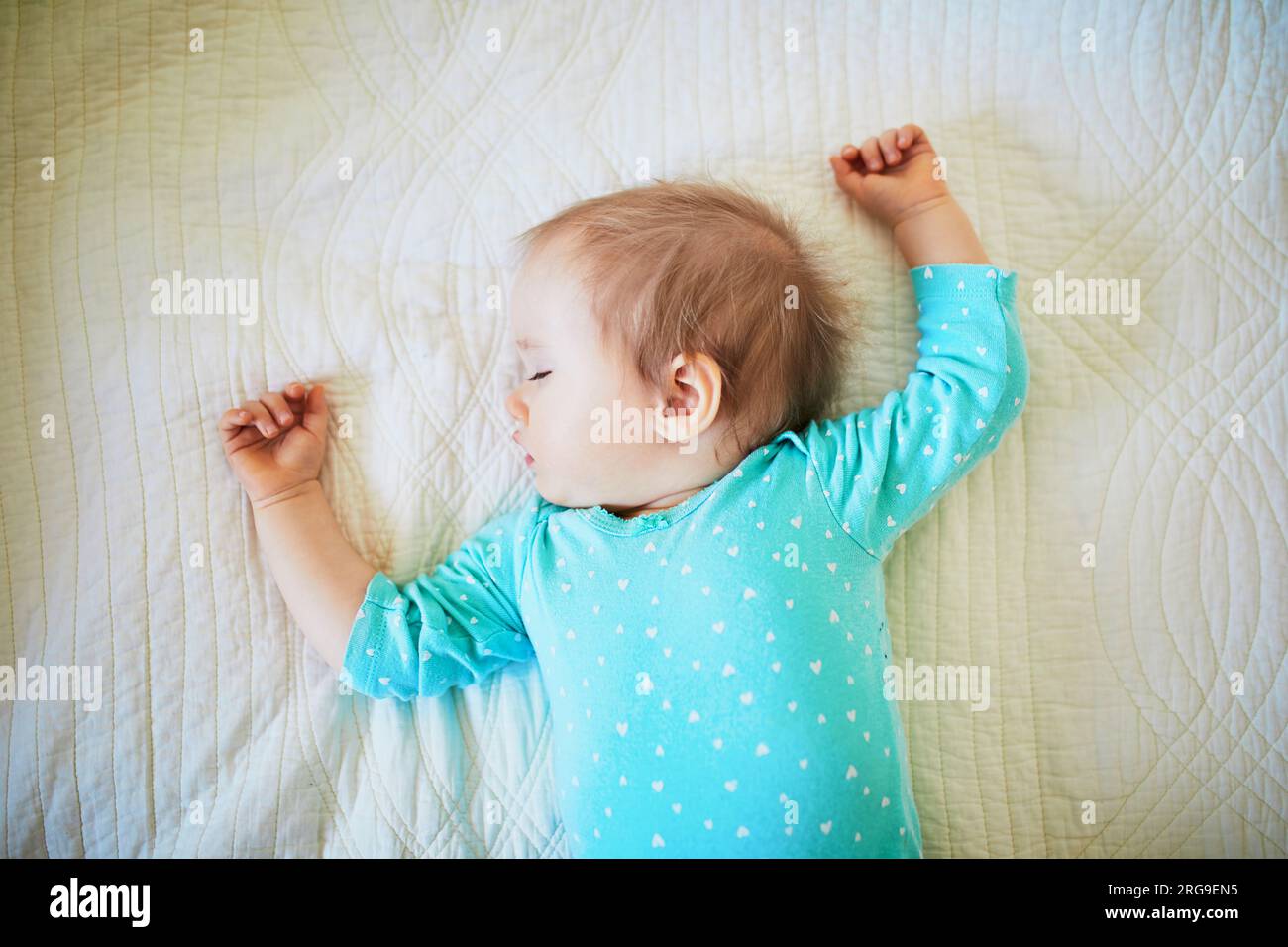 Adorable baby girl sleeping in crib. Small kid having day nap in