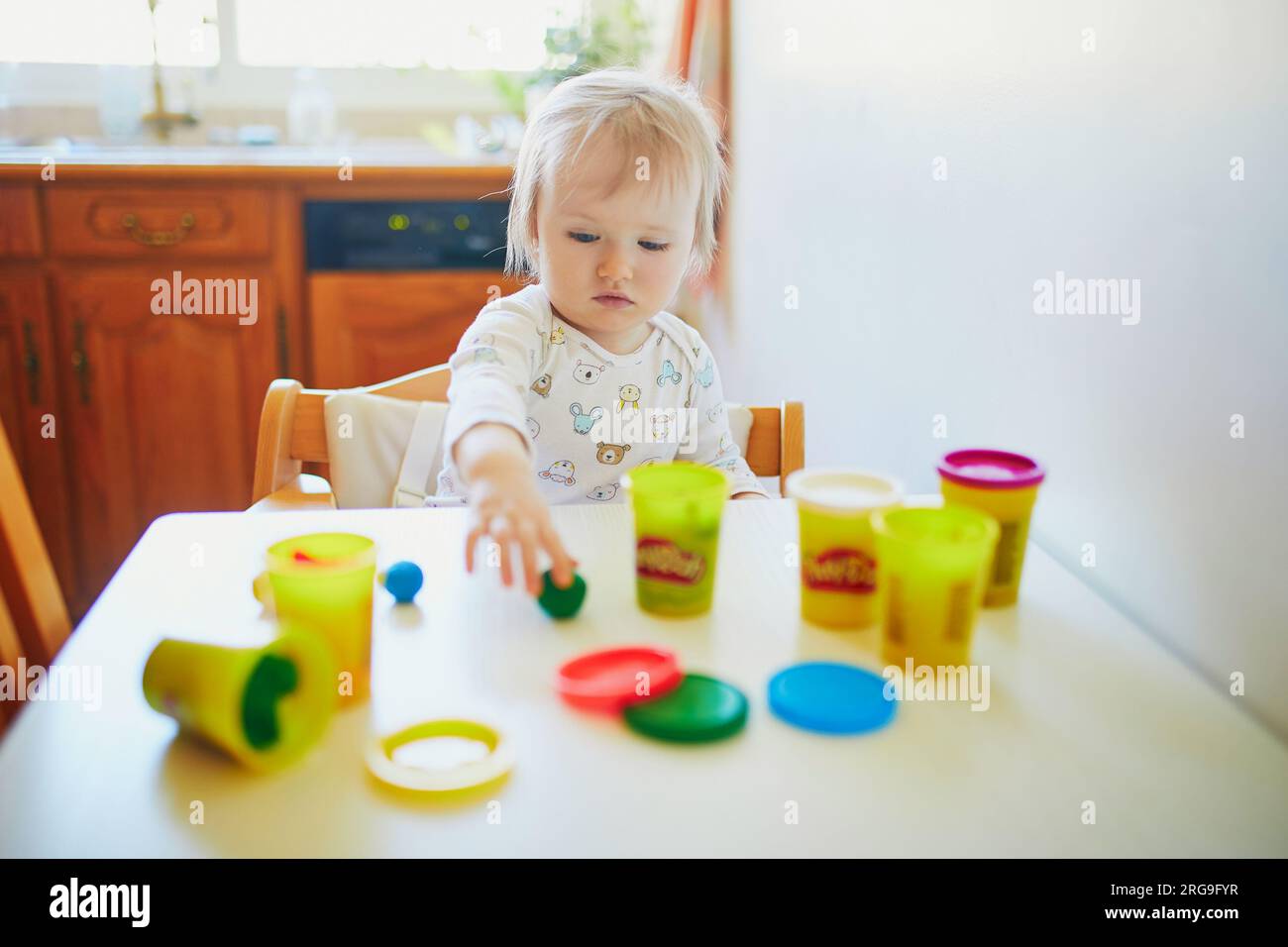 Adorable little girl playing with modelling clay at home. Toddler using