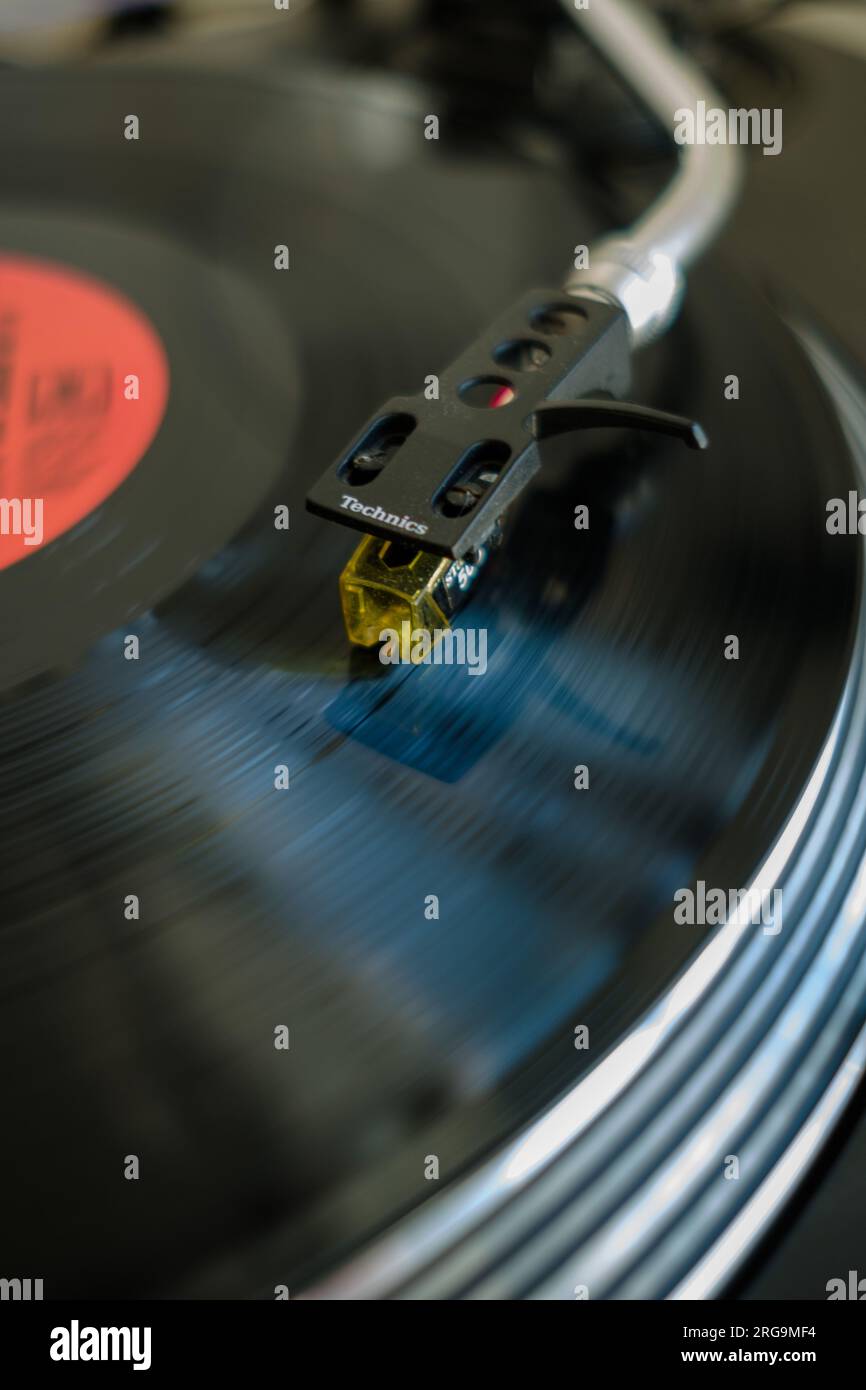Close up Vinyl record playing spinning on Technics 1210 MK2 DJ Deck turntable with motion blur. Stock Photo
