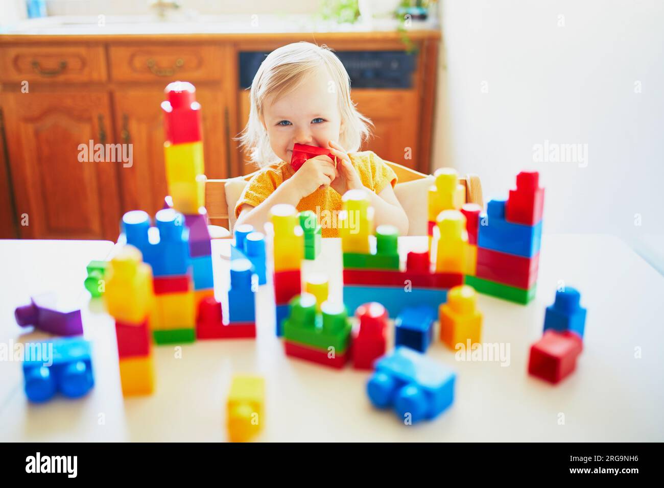 Adorable little girl playing with colorful plastic construction blocks ...