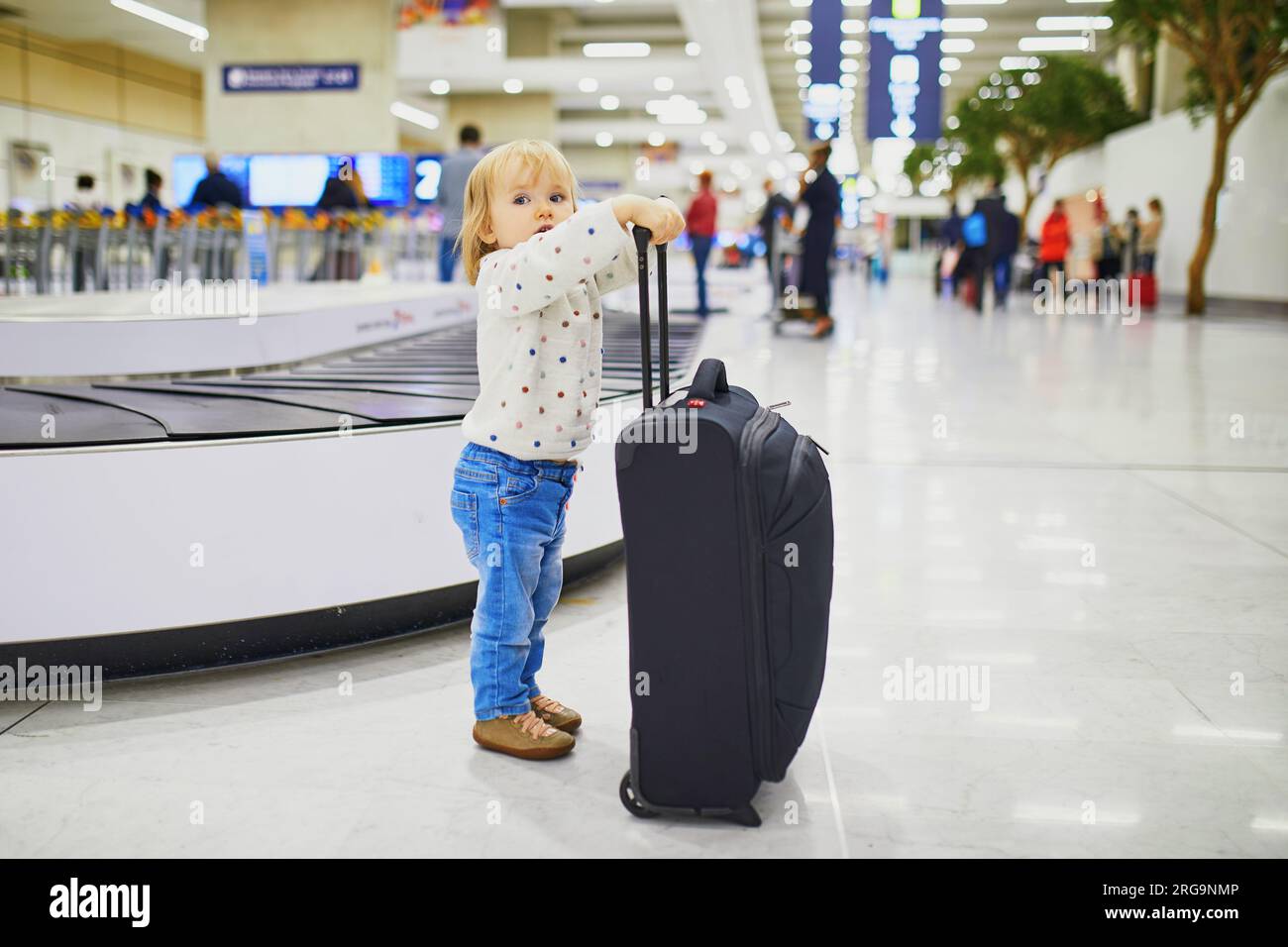 Adorable little girl in the airport. Toddler with carryon luggage. Travelling with small kids