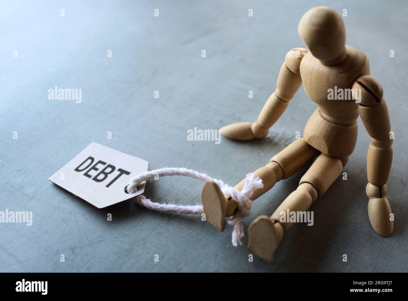 Wooden human figure and tag DEBT. Copy space for text. Finance, debt burden concept. Stock Photo