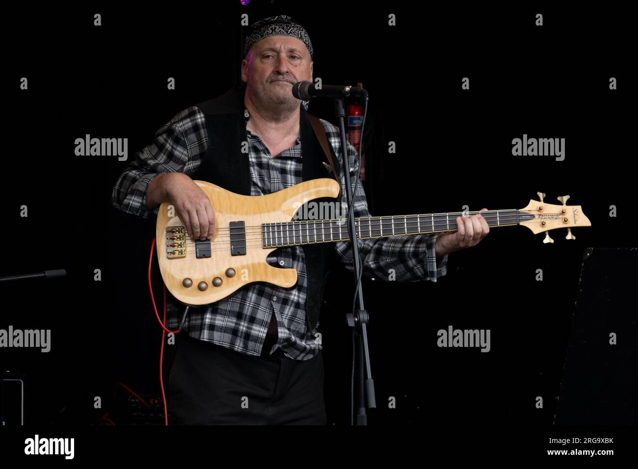 A man playing a Schecter bass guitar at Art in the Park, Leamington Spa