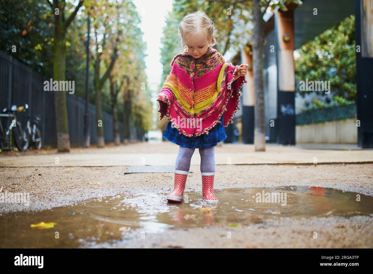 Child wearing red rain boots and jumping in puddle on a fall day ...