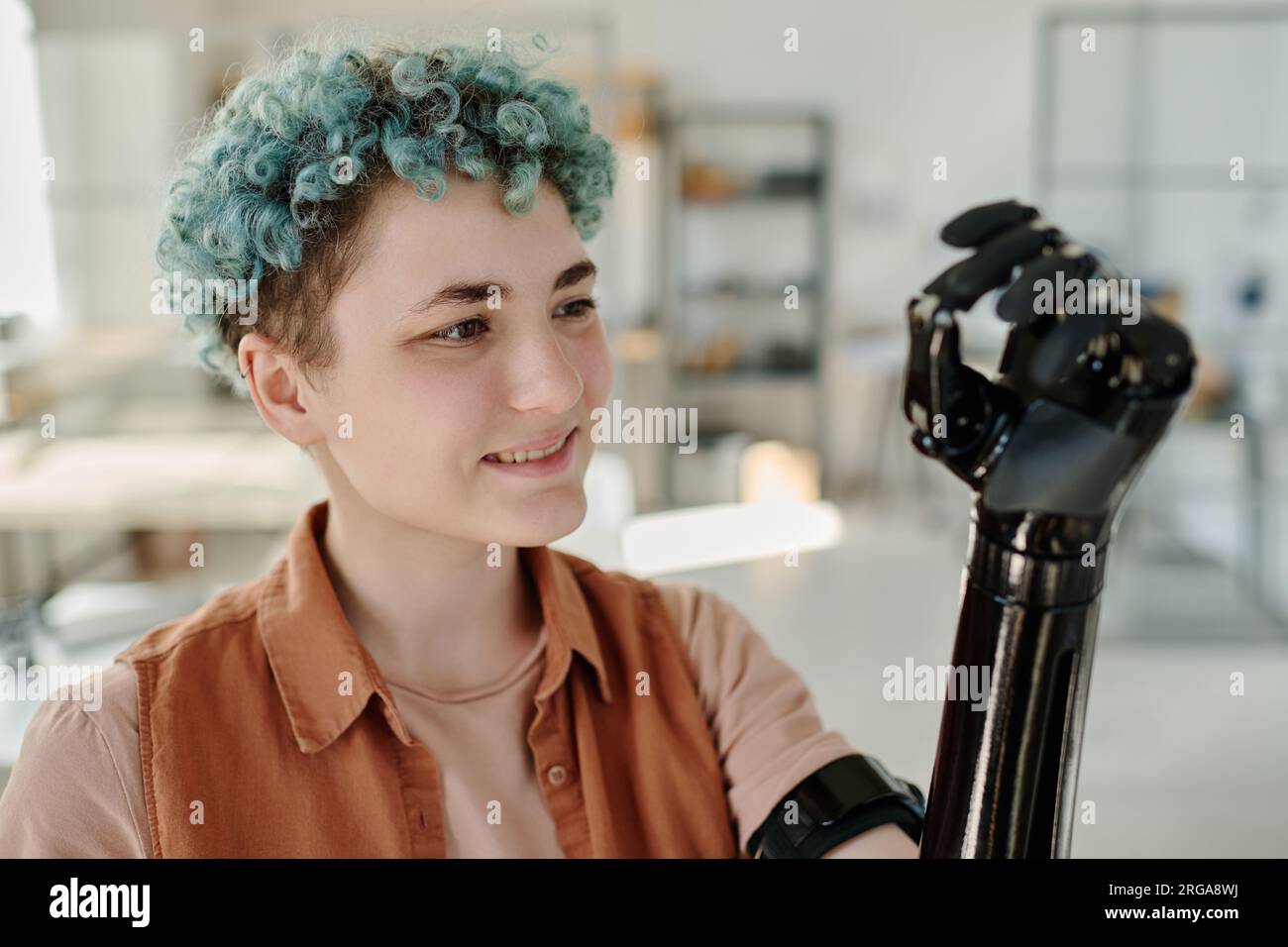 Portrait of young woman looking at cyber prosthetic arm and smiling Stock Photo