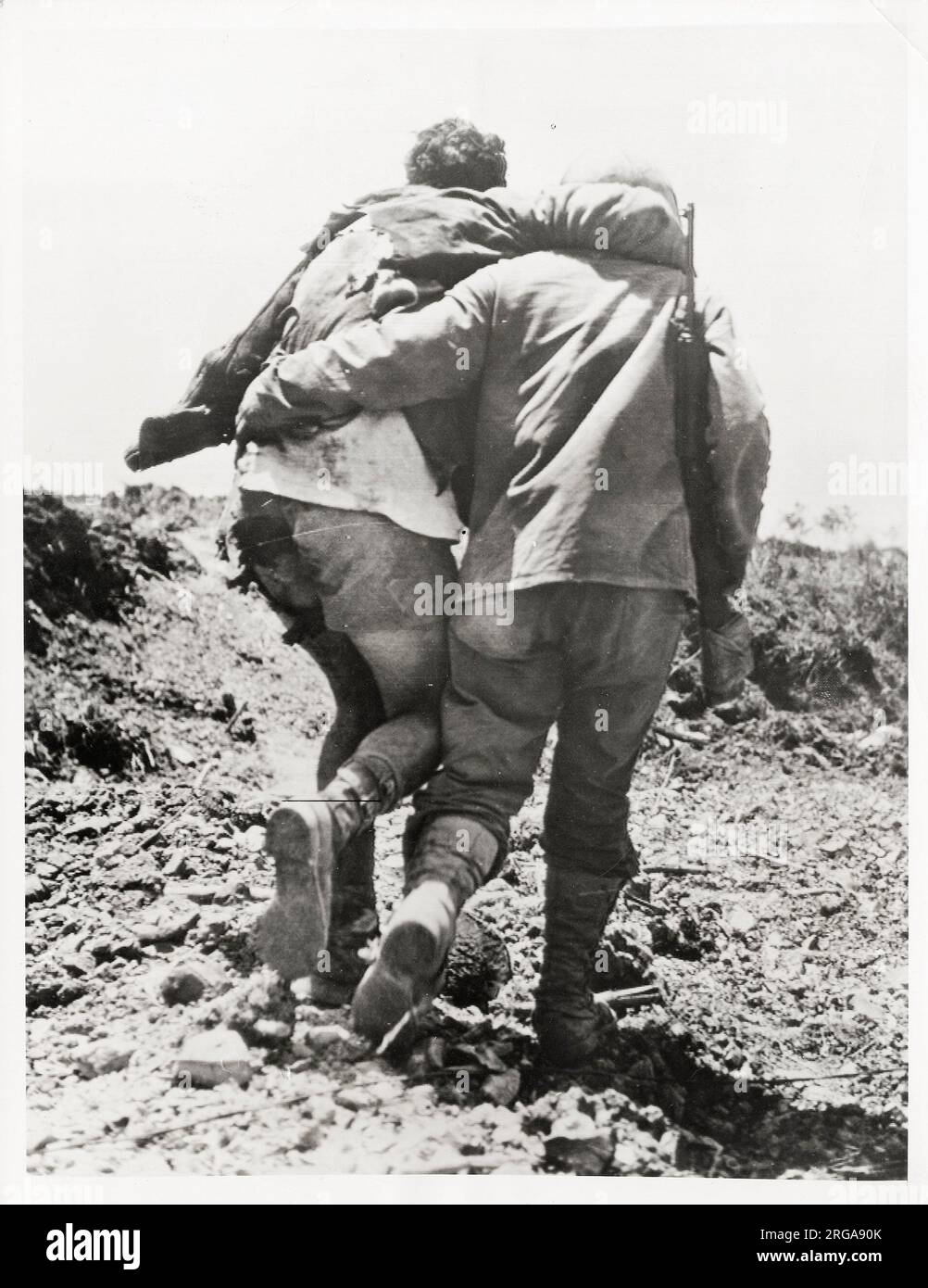 World War II vintage photograph - US soldier with clothes partially blown of is helped towards the rear by comrade. Stock Photo