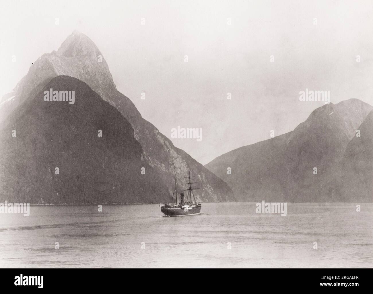 Vintage 19th century photograph: misty morning, Milford Sound New Zealand, boat in the water. Stock Photo