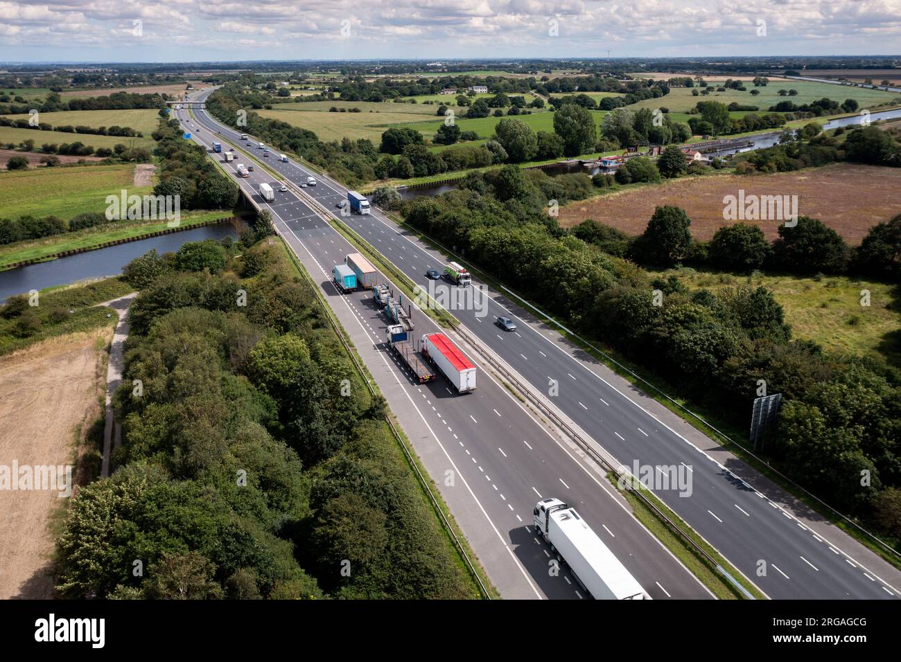 Aerial view directly above the busy M62 motorway spanning a river bridge and countryside whilst heading east towards Hull and stretching into distance Stock Photo