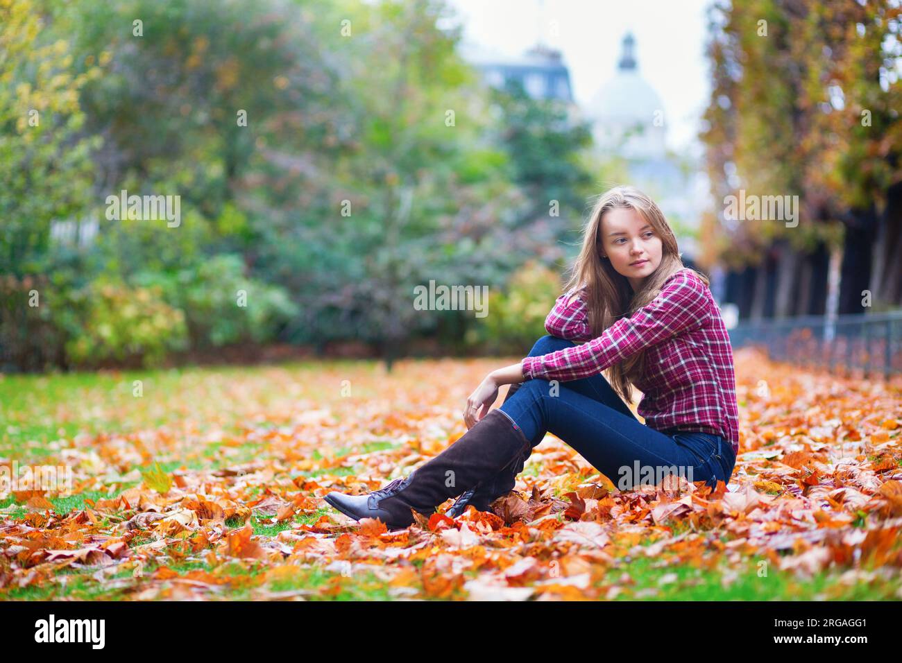 Thoughtful young girl sitting on the ground at fall Stock Photo - Alamy