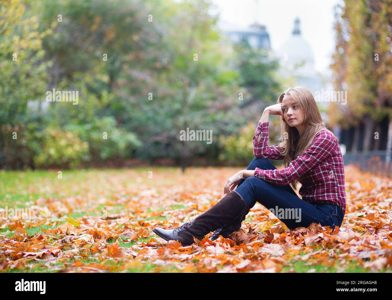 Thoughtful young girl sitting on the ground at fall Stock Photo - Alamy