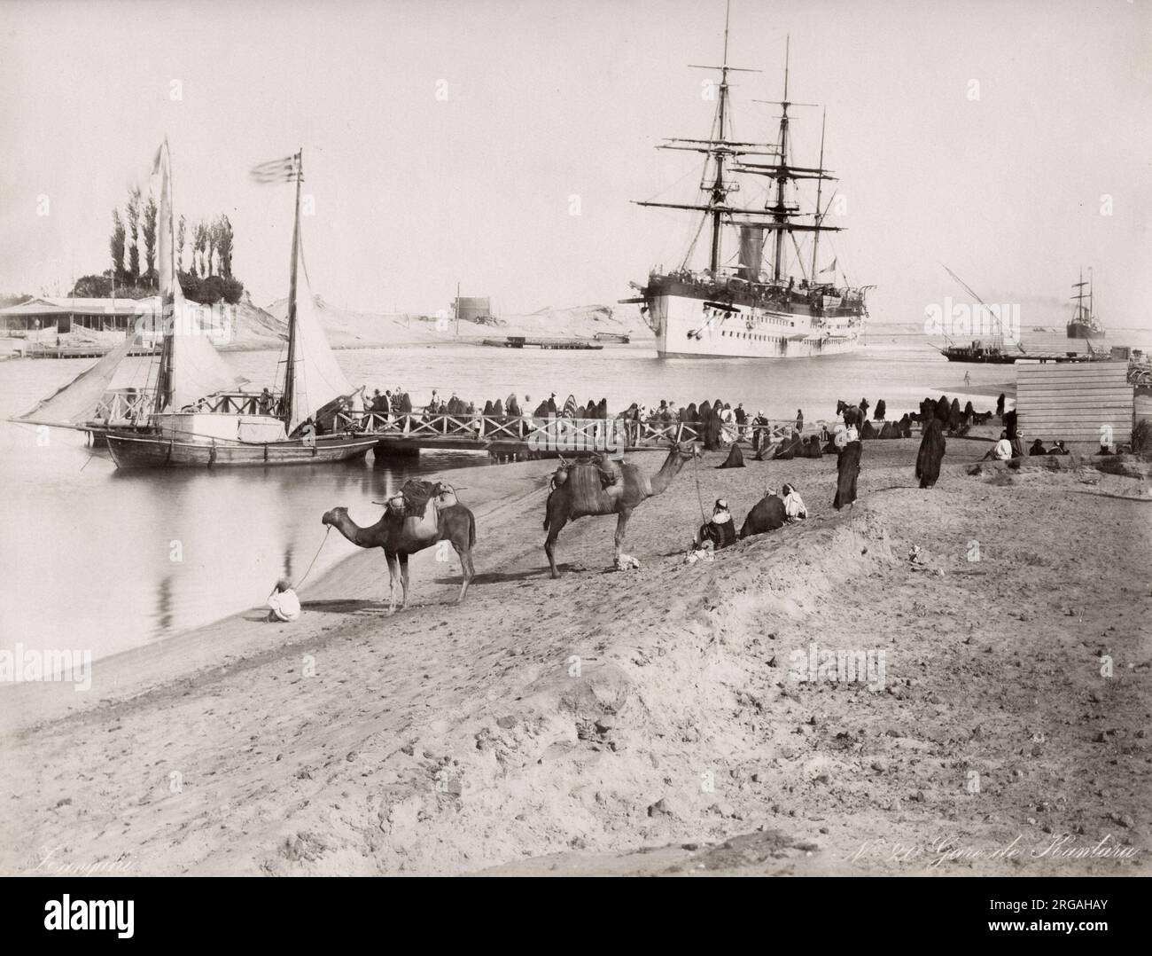 19th century vintage photograph: ship in the Suez Canal, Egyopt. Ferry pier and boat for crossing the canal, camels in the foreground. Stock Photo