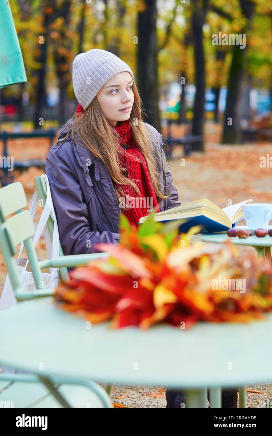 Girl reading a book in an outdoor cafe on a bright fall day in Paris Stock Photo