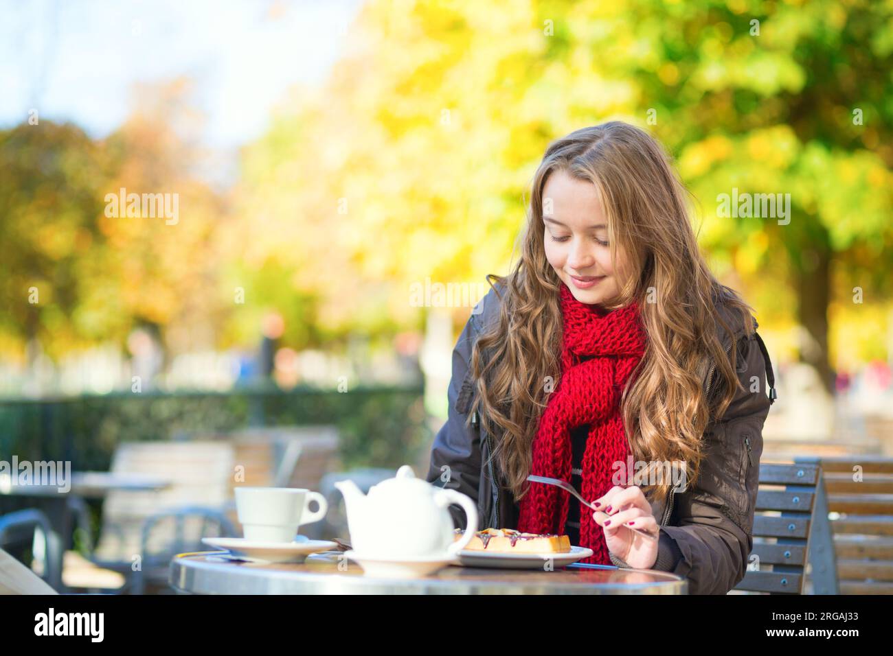 Girl eating waffles in a Parisian outdoor cafe Stock Photo