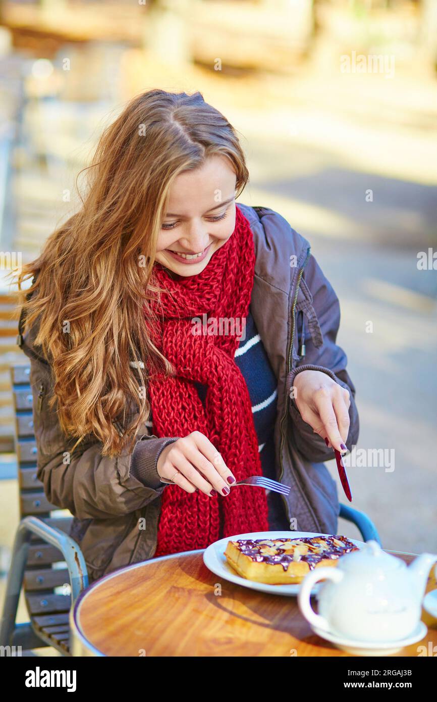 Girl eating waffles in an outdoor Parisian cafe Stock Photo